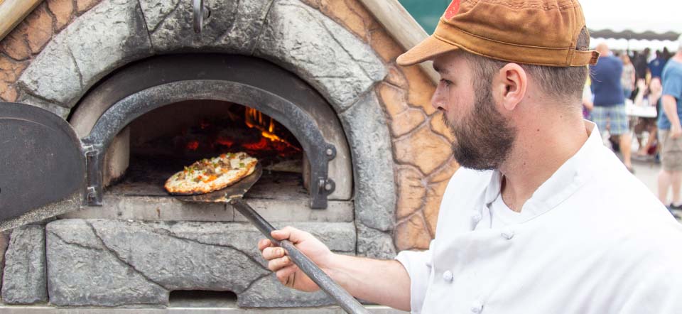 Chef putting a pizza into a wood fire oven.